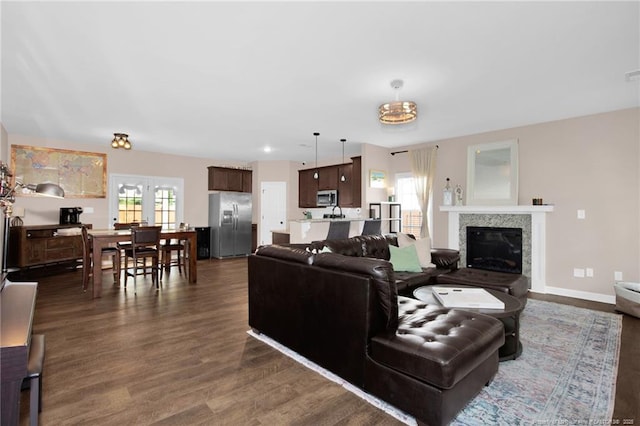 living room with a glass covered fireplace and dark wood-type flooring