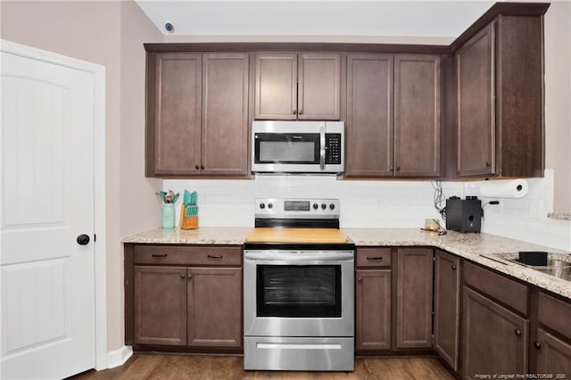 kitchen featuring stainless steel appliances, dark wood-type flooring, and backsplash