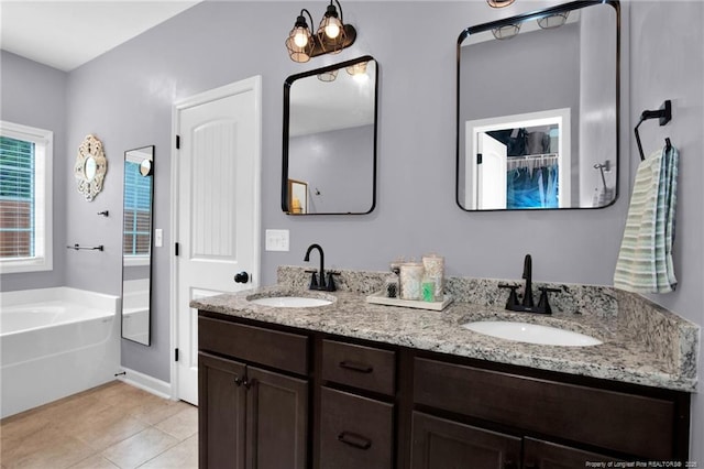 bathroom with tile patterned flooring, a garden tub, double vanity, and a sink