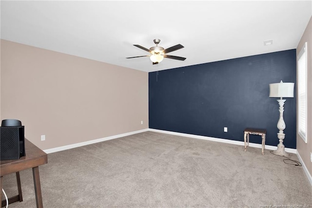 spare room featuring carpet, baseboards, and a ceiling fan