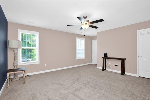 carpeted empty room with a ceiling fan, baseboards, and visible vents