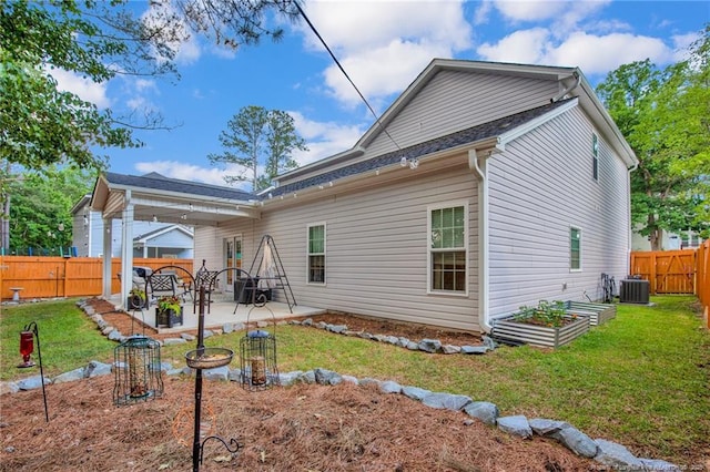 back of house with a lawn, a patio area, a fenced backyard, and a vegetable garden