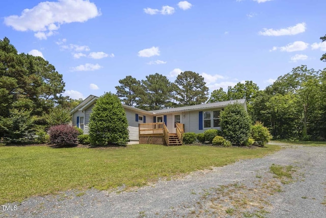 view of front of home with a wooden deck, a front yard, and driveway