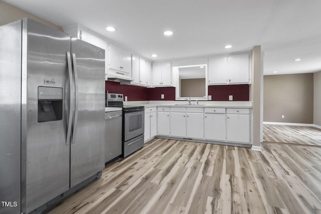 kitchen featuring stainless steel appliances, under cabinet range hood, light wood-style floors, white cabinets, and recessed lighting