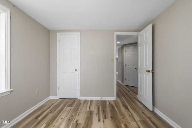 unfurnished bedroom with light wood-type flooring and baseboards