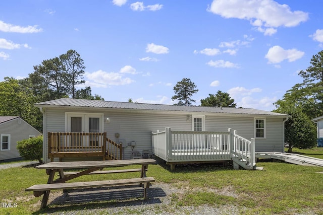 rear view of property with a wooden deck, metal roof, and a lawn