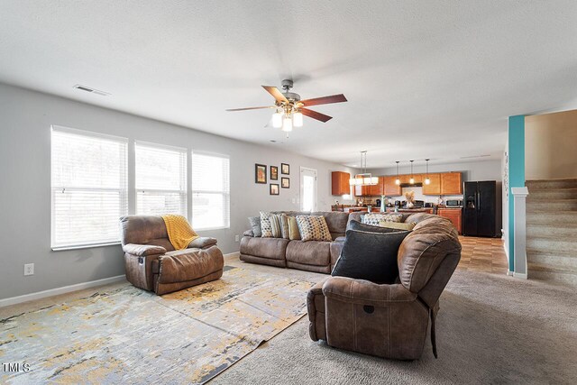 living room with a ceiling fan, baseboards, and stairway