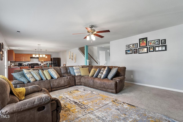 living area with a ceiling fan, baseboards, stairs, light colored carpet, and a chandelier