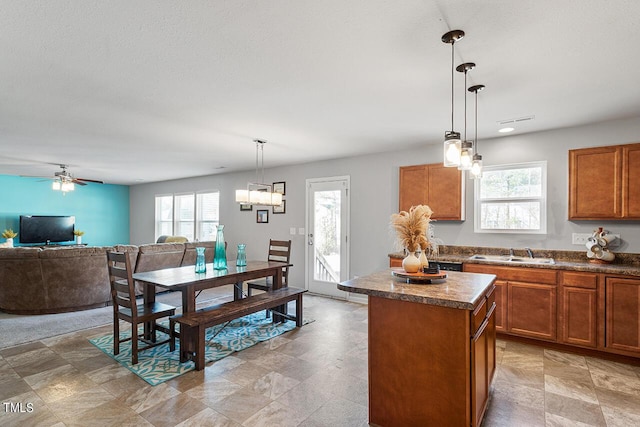 kitchen with a sink, a kitchen island, brown cabinetry, dark countertops, and open floor plan