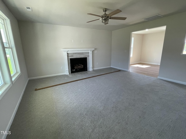 unfurnished living room with ceiling fan, a high end fireplace, visible vents, and carpet floors