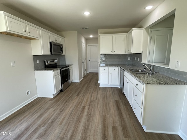 kitchen with light stone counters, a sink, dark wood-type flooring, tasteful backsplash, and appliances with stainless steel finishes