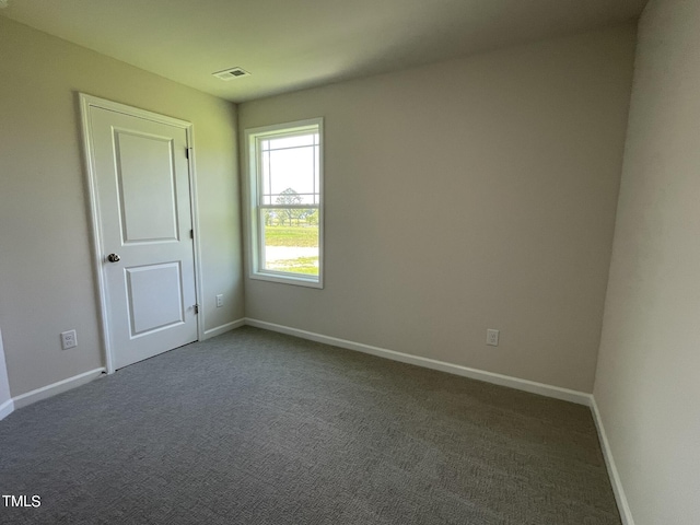 unfurnished room featuring baseboards, visible vents, and dark carpet