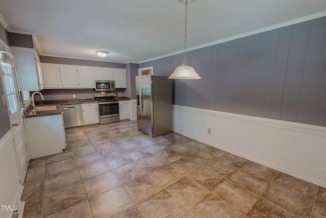 kitchen with stainless steel appliances, a sink, dark countertops, white cabinets, and pendant lighting