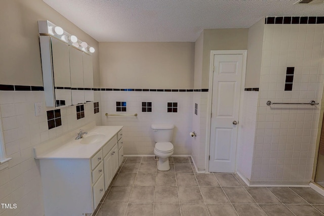 full bath featuring tile walls, a textured ceiling, toilet, tile patterned floors, and vanity