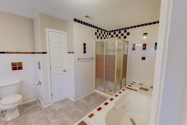 full bath with tile walls, a stall shower, a textured ceiling, toilet, and tile patterned floors
