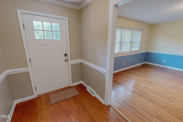 entryway with wood finished floors, baseboards, and crown molding