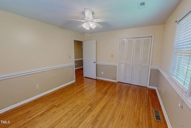 unfurnished bedroom with light wood-style flooring, a closet, baseboards, and a ceiling fan