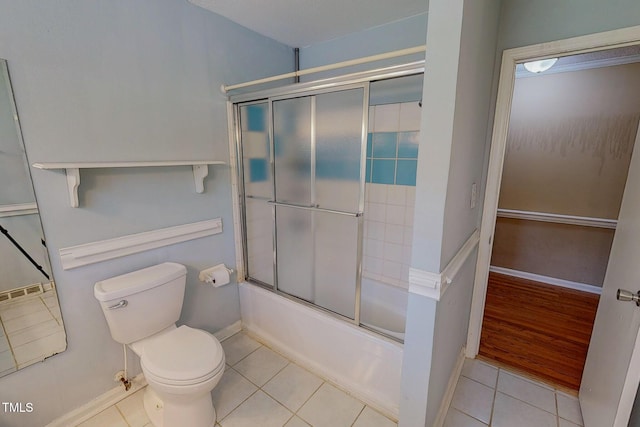 full bath with tile patterned floors, toilet, combined bath / shower with glass door, and baseboards