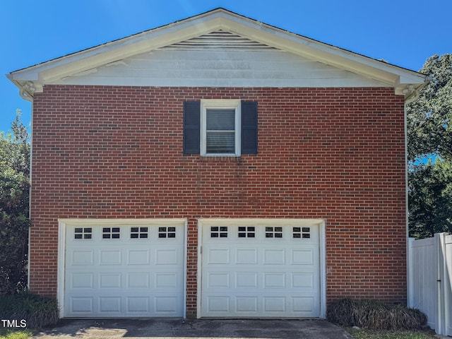 view of property exterior featuring brick siding, an attached garage, and fence