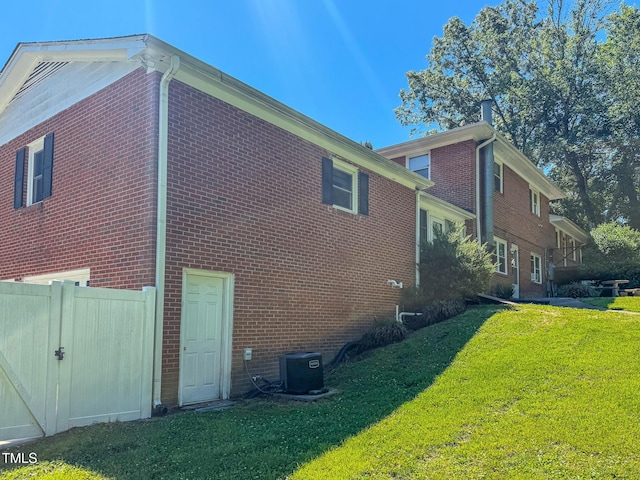 view of side of home featuring a yard, central AC, and brick siding