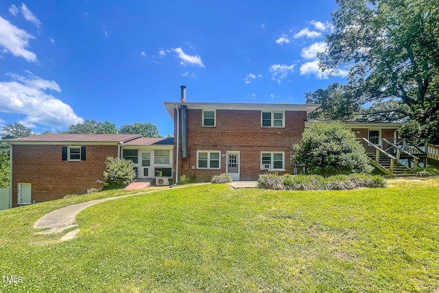back of house with brick siding and a yard