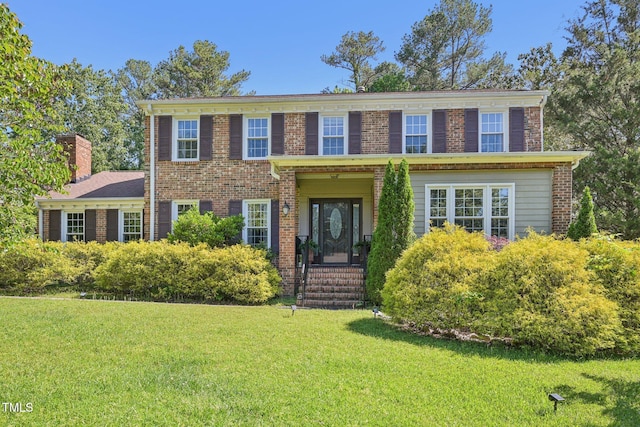view of front of property with a front lawn, a chimney, and brick siding