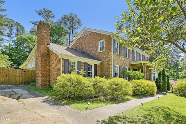 view of side of home with brick siding, fence, and a chimney
