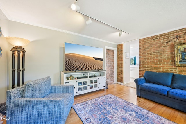 living area featuring brick wall, rail lighting, and wood finished floors