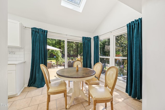dining room featuring a skylight, light tile patterned flooring, and lofted ceiling
