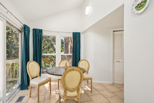 dining space with light tile patterned flooring, high vaulted ceiling, and baseboards
