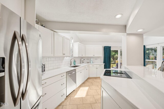 kitchen featuring stainless steel appliances, a sink, decorative backsplash, white cabinetry, and light countertops