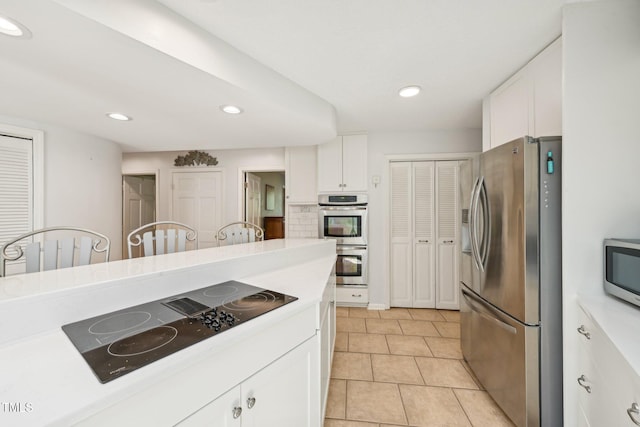 kitchen with appliances with stainless steel finishes, white cabinetry, light countertops, recessed lighting, and light tile patterned floors