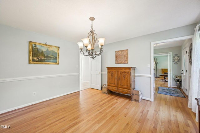 dining room with a chandelier, light wood-style flooring, and baseboards