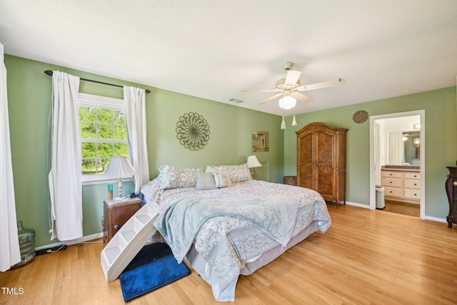bedroom with wood finished floors, a ceiling fan, baseboards, and connected bathroom