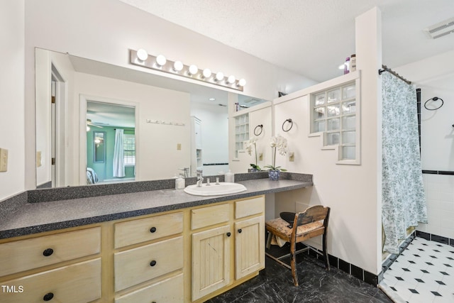 full bath with a shower with curtain, vanity, and marble finish floors