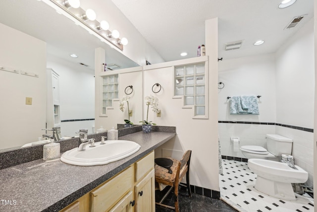 bathroom featuring a bidet, toilet, recessed lighting, vanity, and wainscoting