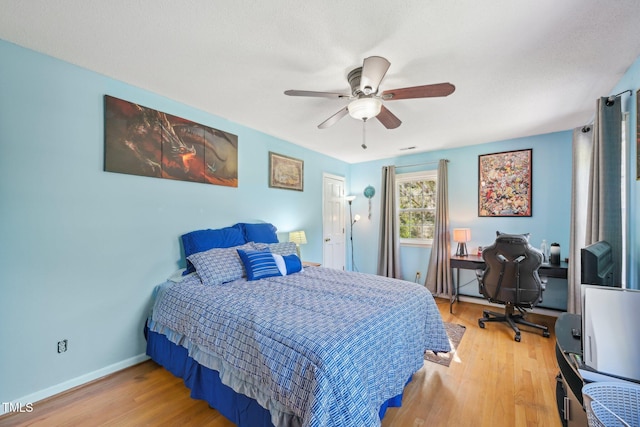 bedroom with wood finished floors, baseboards, ceiling fan, and an office area