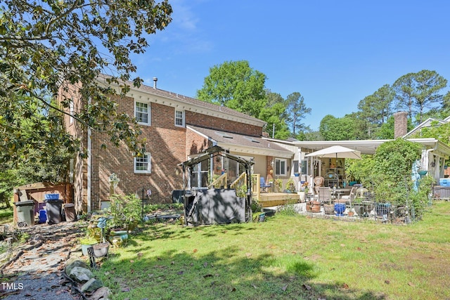 back of house featuring brick siding and a lawn