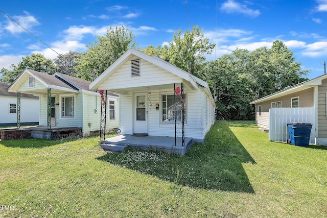 shotgun-style home featuring covered porch and a front yard