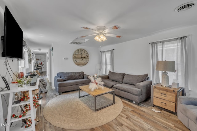 living area with light wood-type flooring, ceiling fan, and healthy amount of natural light
