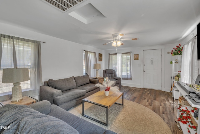 living room featuring wood finished floors, a skylight, and a ceiling fan