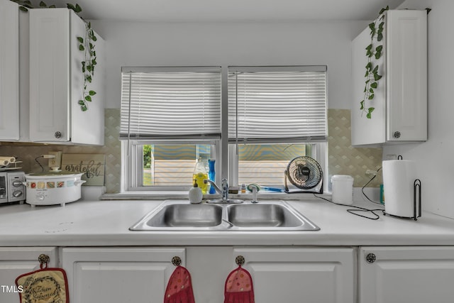 kitchen featuring a sink, white cabinetry, light countertops, and tasteful backsplash