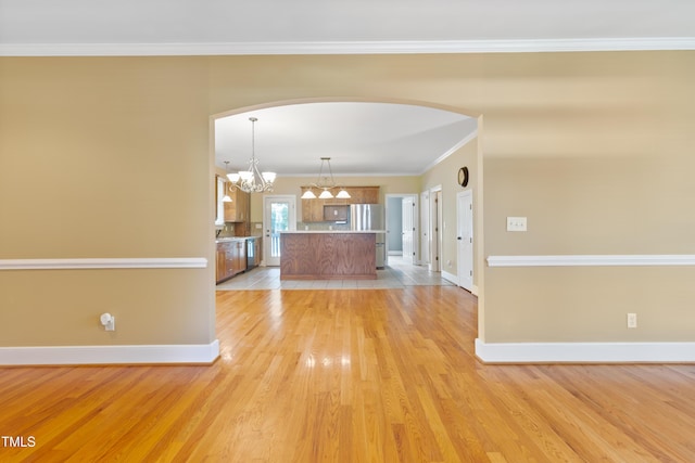 207 N Hopkins Ave, Spring Hope, NC 27882 - unfurnished living room featuring a chandelier, light wood-type flooring, arched walkways, baseboards, and ornamental molding