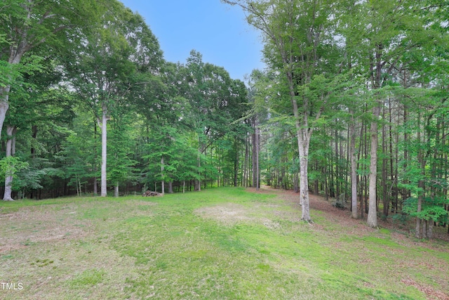 view of grassy yard featuring a wooded view