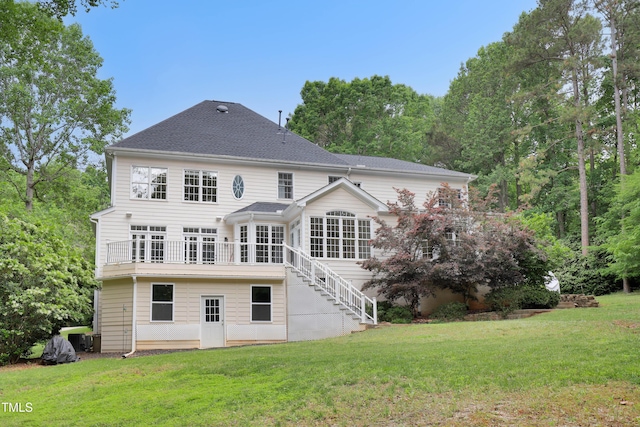 rear view of house with a yard, stairs, and a shingled roof