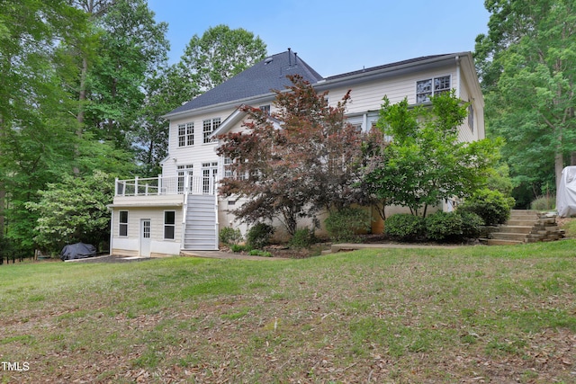 rear view of house with stairs, a lawn, and a deck