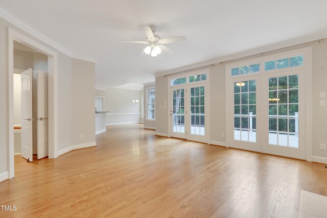 empty room with a ceiling fan, baseboards, light wood-type flooring, healthy amount of natural light, and crown molding