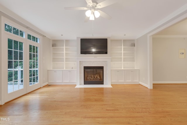 unfurnished living room featuring built in shelves, ornamental molding, plenty of natural light, and baseboards