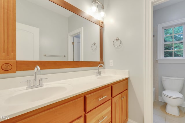 bathroom featuring toilet, tile patterned floors, double vanity, and baseboards