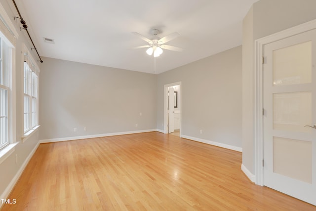 spare room with ceiling fan, light wood-style floors, and baseboards